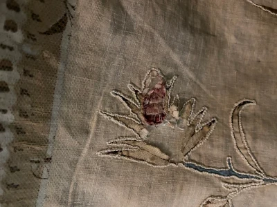 Detail of a stitched leaf on a historic quilt showing wear to the cotton and discolouration of the base fabric.