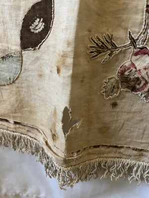 Detail showing holes, brown marks and discolouration to the cotton of Cowper's historic quilt.