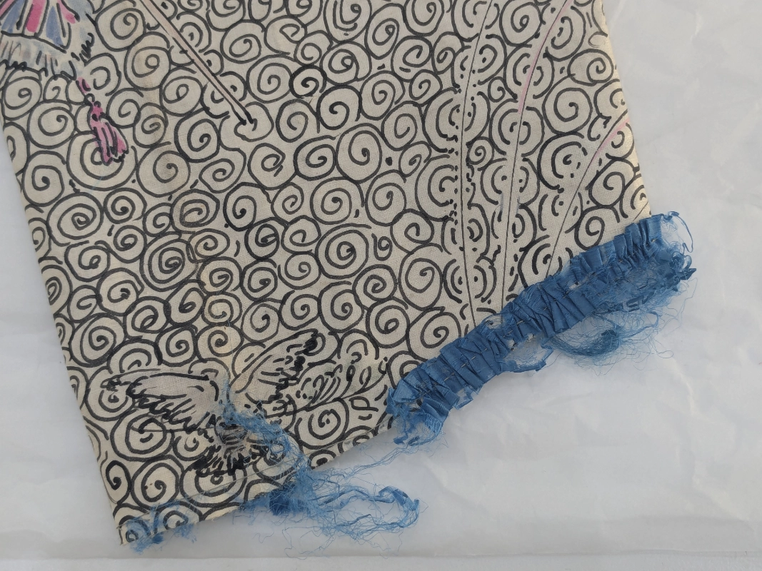 Sleeve detail before conservation with loose and worn ribbon trim