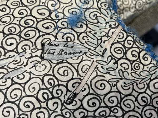 Swirled painted pattern with handwritten text "Here Lies the Brave"