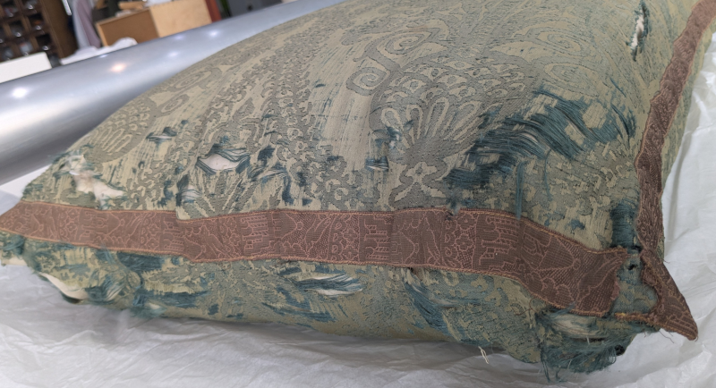 Torn silk damask cushion in need of conservation