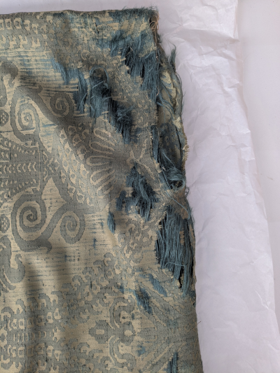 Corner detail of silk damask cushion showing torn silk