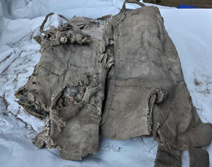 Fragile and dirty historic textile remnants laid out on white tissue paper