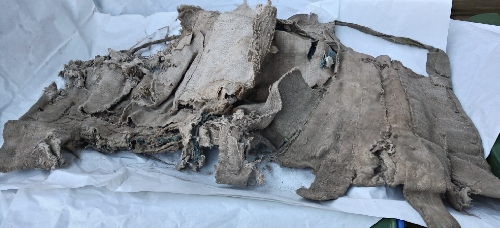 Image of distressed cloth laid out on tissue paper forming the remnants of an antique pair of stays